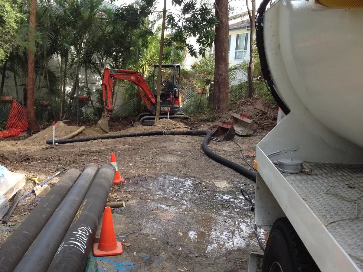 Vacuum truck and hose positioned beside an excavation work area