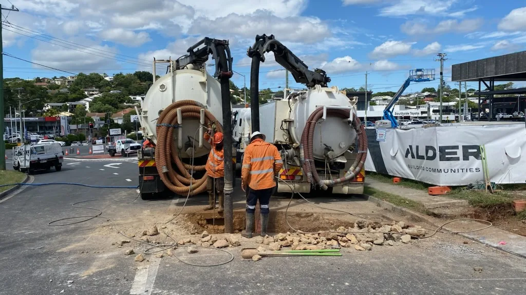 Two VACIT crew members operating vacuum trucks on a civil worksite